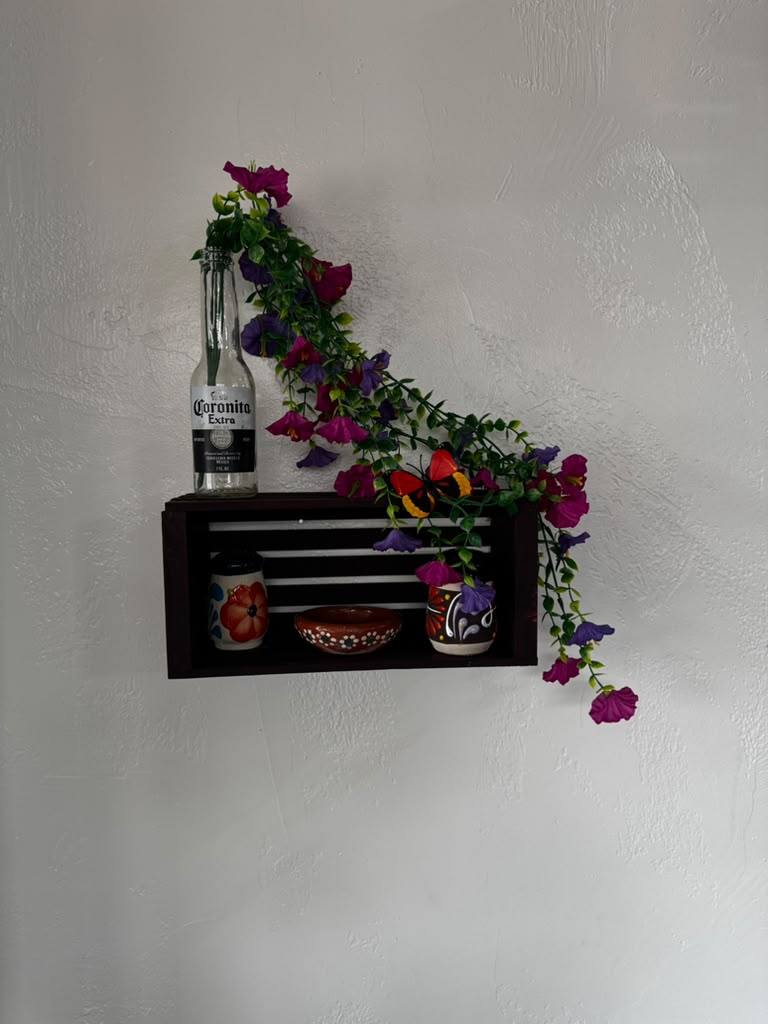Wall shelf with a Coronita bottle, painted Mexican pottery and bright flowers